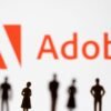 Figurines are seen in front of displayed Adobe logo in this illustration taken June 13, 2022. REUTERS/Dado Ruvic/Illustration/File Photo