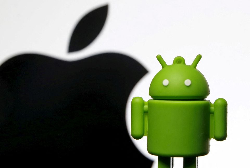 An Android mascot is seen in front of a displayed logo of Apple in this photo illustration taken in Zenica, Bosnia and Herzegovina, May 5, 2015. Picture taken on May 5. REUTERS/Dado Ruvic/File Photo